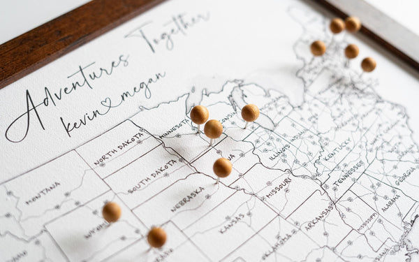 High-resolution close-up of framed 11x14" USA push pin map with wooden pins, featuring black-and-white design with labeled U.S. states and interstate highways. Desk-sized personalized map for tracking travels and adventures.