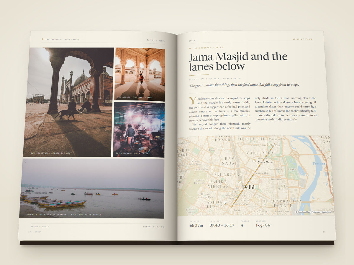 The same A4 portrait softcover Travel Book, open on the table. Two printed pages — A moment page — four photographs of the great mosque in Delhi, its arcade, a smoky kitchen and boats on the river, each captioned, facing the title, an essay about the morning, a street map of Old Delhi with the walk drawn on it and the hours on site
