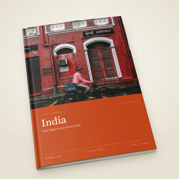 kr-paper:kr-maps-travel-book-a4-portrait-softcover:hero:8271a915 — An A4 portrait softcover KR Maps Travel Book, closed on a table — a book of four days across Delhi, Agra and Jaipur, the title set over one of the trip's own photographs