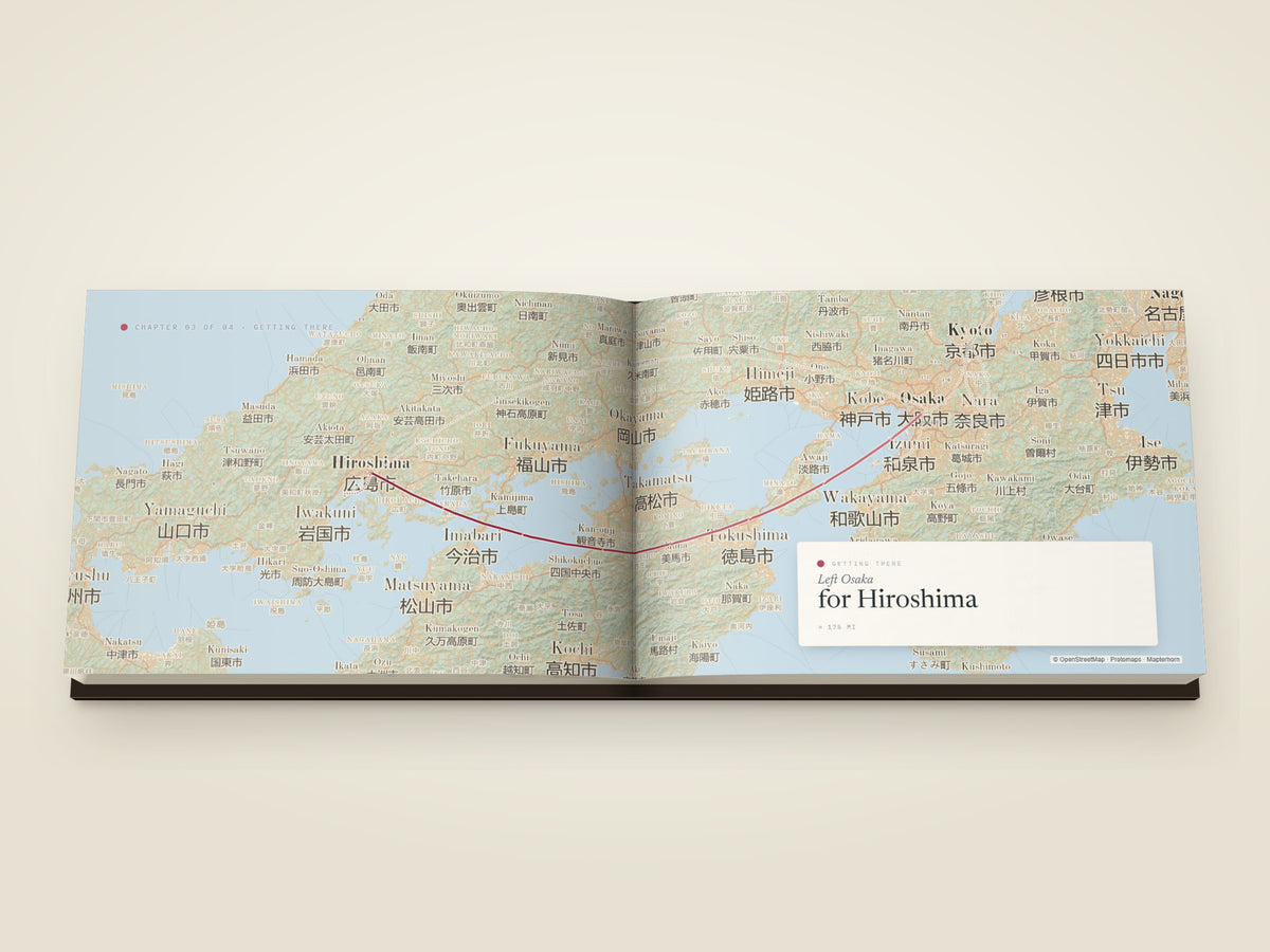 The same A5 landscape hardcover Travel Book, open on the table. A getting-there spread — the leg from Osaka to Hiroshima drawn as a single arc across a map filling both printed pages, with a card noting the departure