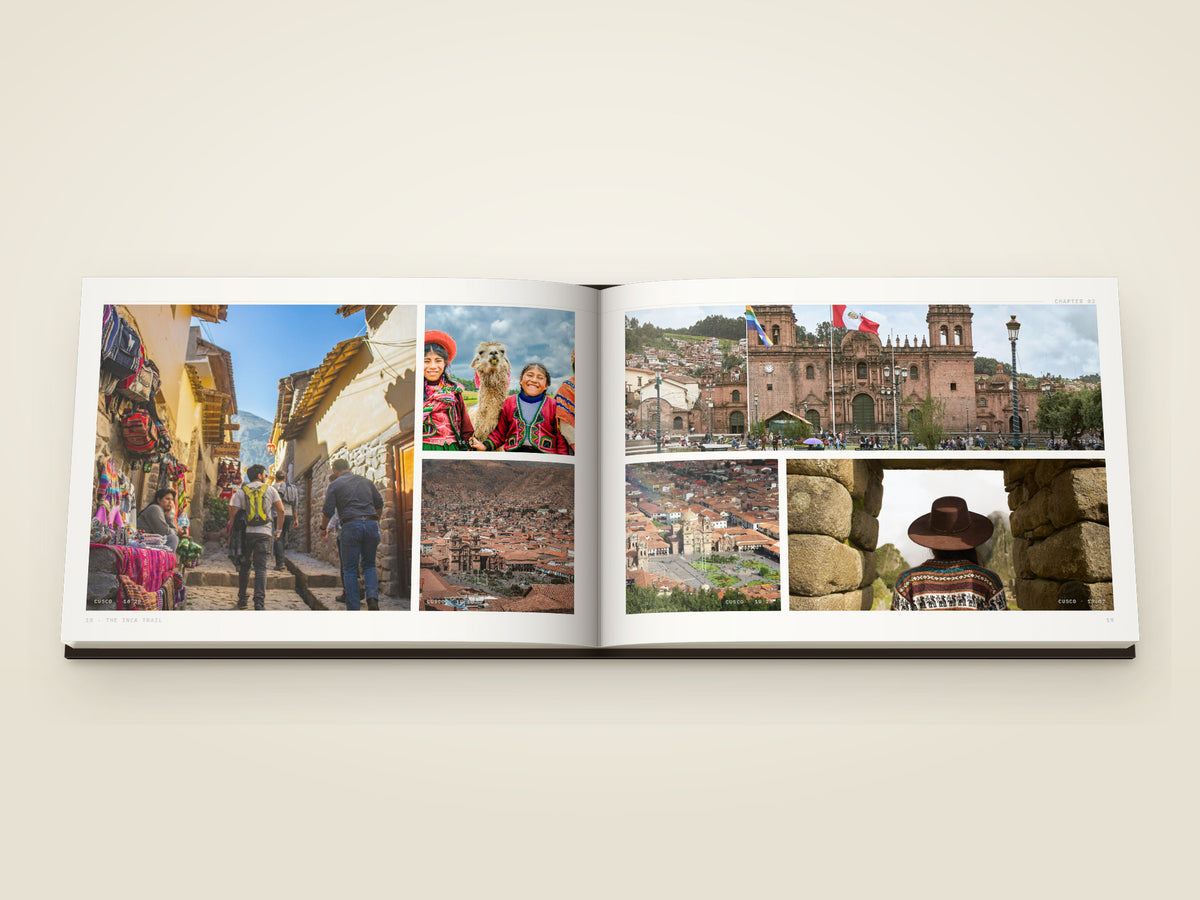 The same A4 landscape hardcover Travel Book, open on the table. Two printed pages — six photographs from Cusco — a narrow street of stone walls and woven blankets, two women in red with a llama, terracotta rooftops, the cathedral on its square, the square from above and a figure in a stone doorway