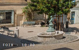 A printed page, close on a fountain square in Foix, stamped FOIX · 10:00