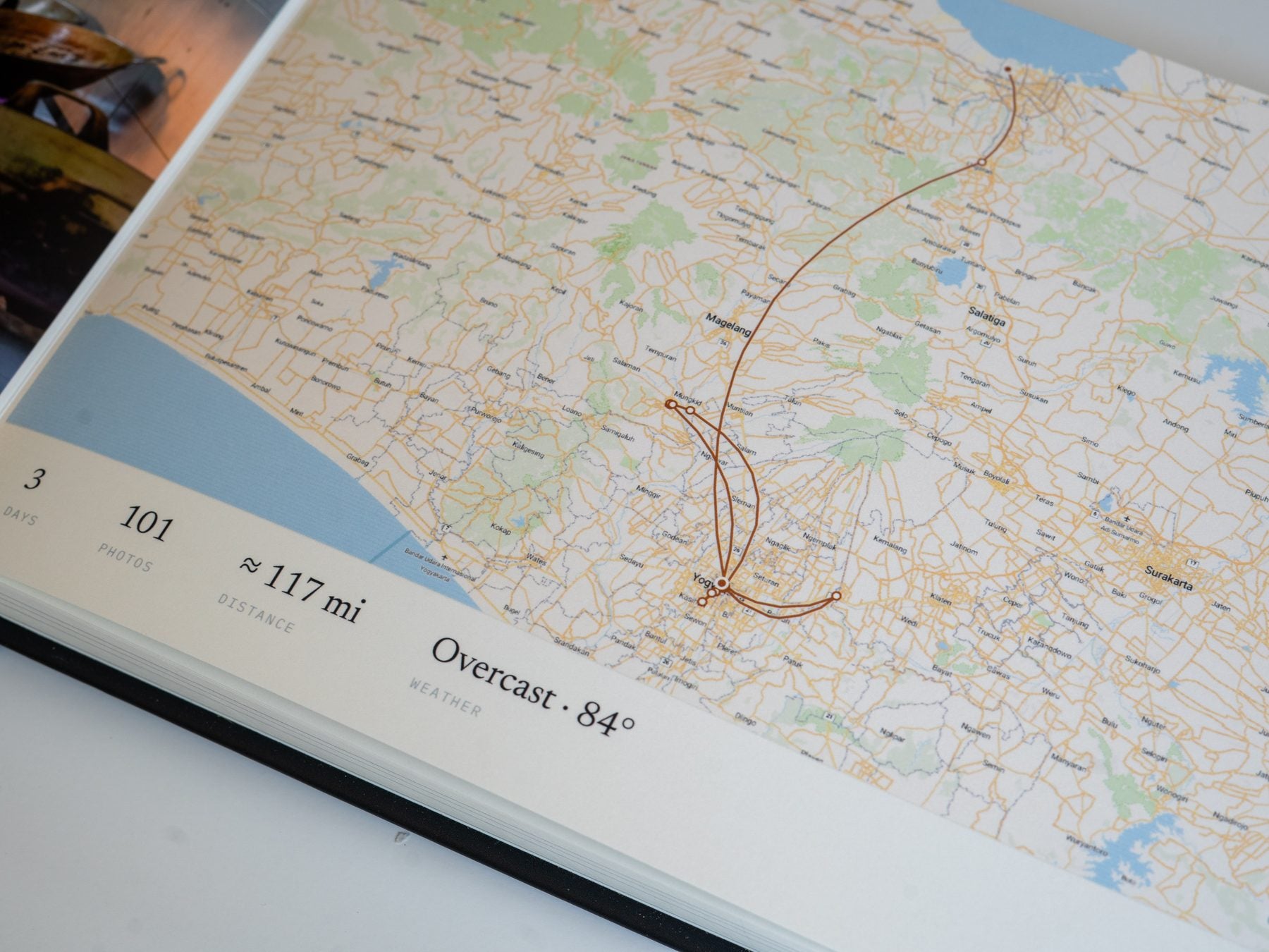 A printed map page at an angle, the route line looping out and back above the day ledger