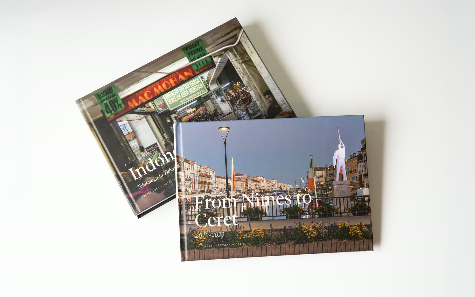 Two finished Travel Books with different covers, one resting across the other on a white surface