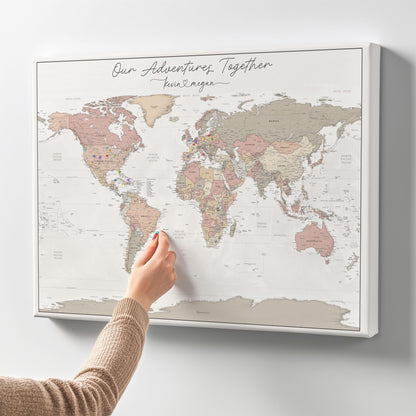 A personalized push pin travel map featuring a high-quality canvas or pinboard. The map displays a custom title and names connected by a heart symbol. The map is shown without a frame, highlighting its durable foam backing.