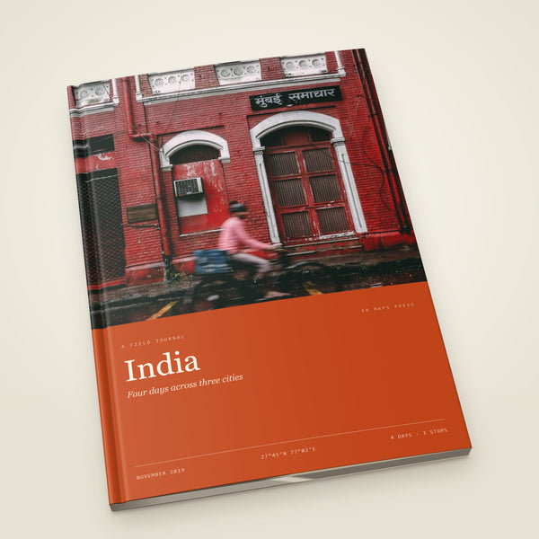 kr-paper:kr-maps-travel-book-a4-portrait-softcover:hero:99185c9e — A A4 portrait softcover KR Maps Travel Book, closed on a table — a book of four days across Delhi, Agra and Jaipur, the title set over one of the trip's own photographs