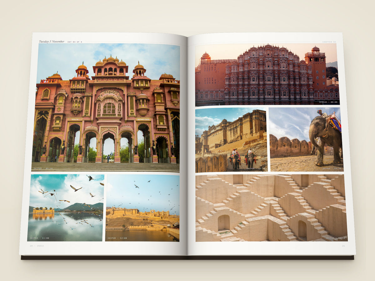 The same A4 portrait softcover Travel Book, open on the table. Two more printed pages, from Jaipur — the carved arches of Patrika Gate, the pink screen of Hawa Mahal, elephants climbing to Amber Fort, the Water Palace standing in its lake, the fort across the water and the stepped walls of a stepwell
