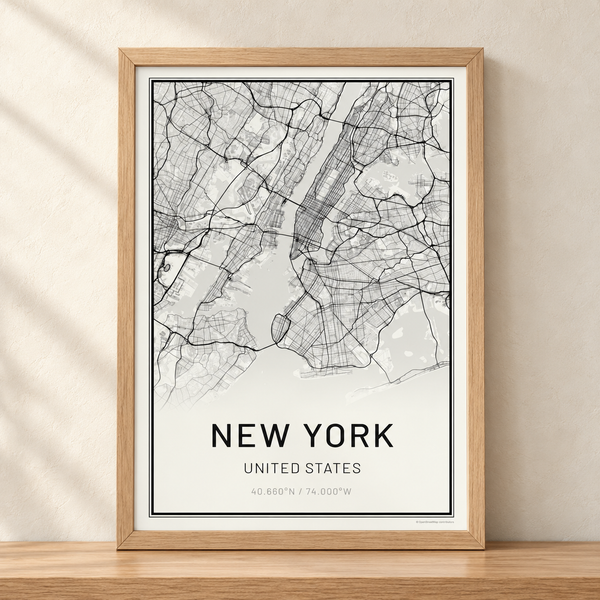 Black and white New York street map poster in a white oak frame, standing on a wooden shelf